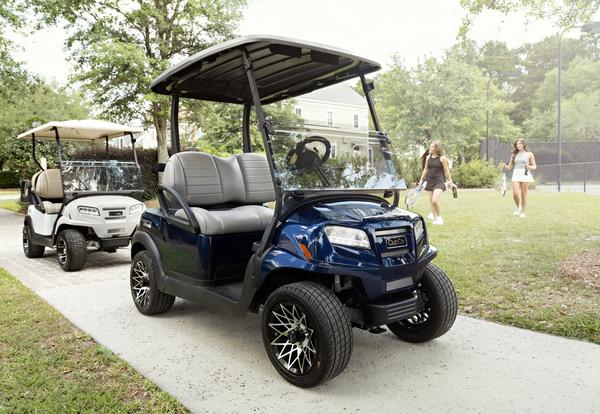 Golf buggy Onward from Club Car parked in front of a hotel complex.