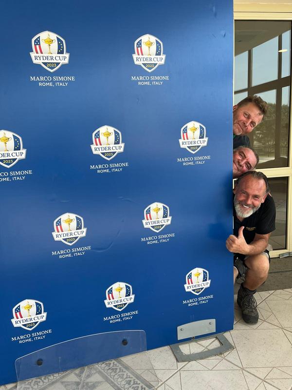 Mitarbeiter der Cart Care beim Ryder Cup in Rom hinter einer Ryder Cup Logowand.